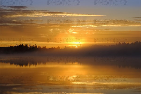 Sunrise with early morning mist over Kirchsee with Reutberg Monastery