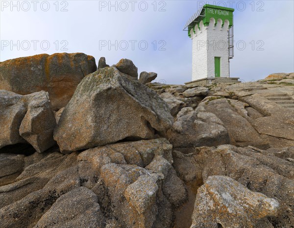 Green and white lighthouse on granite rocks