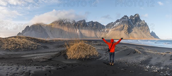 Man in red jacket stretches arms into the air