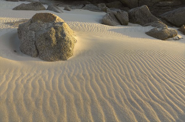 Granite rocks in the sand with wave structure