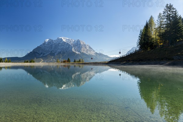 Water reservoir for snow production for the ski slopes on Grubigstein with view to the Zugspitze and mountain railway