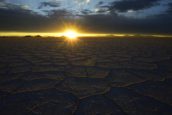 Honeycomb structure on the salt lake at sunset with clouds