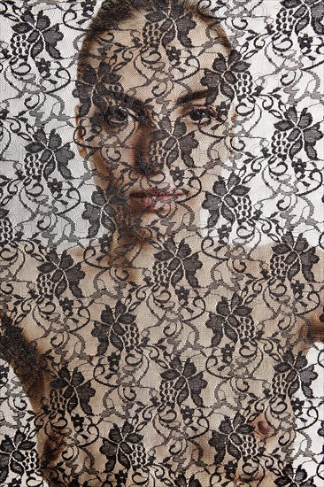 Nude woman behind a transparent cloth with floral pattern