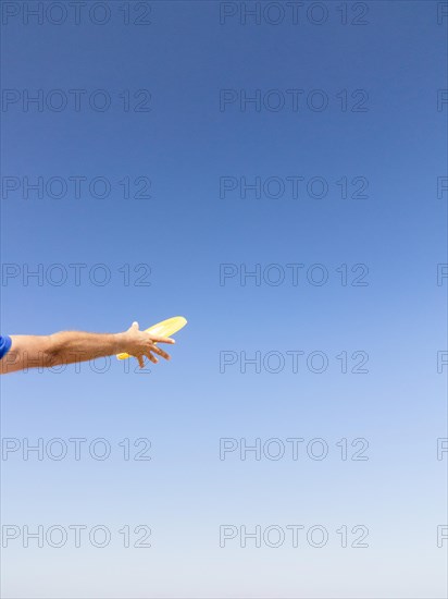 Man catching a frisbee against blue sky
