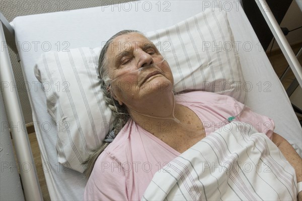 Sleeping senior citizen with respiratory tube in bed in hospital