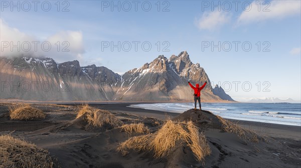 Man in red jacket stretches arms into the air