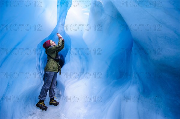 Woman photographing in a ice cave in Fox Glacier