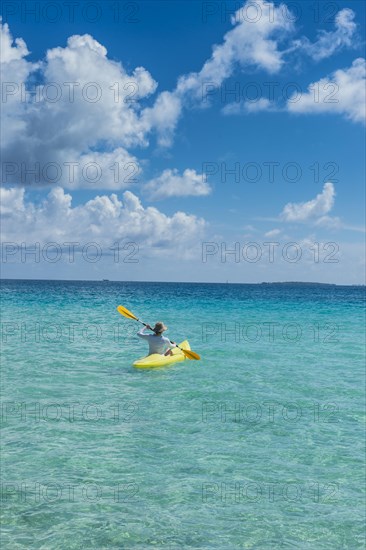 Female tourist kayaking in the turquoise waters of Tikehau