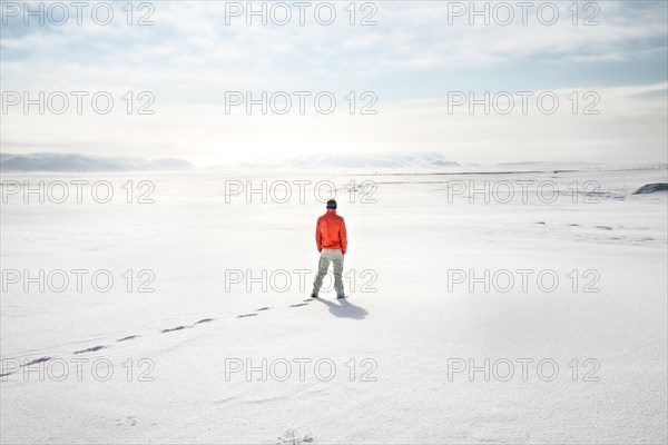 Young man stands alone in snowy landscape