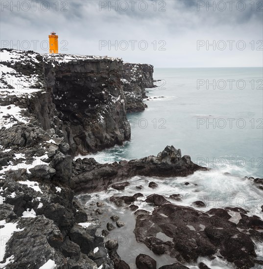 Orange lighthouse Ondverdarnes stands on a dark cliff