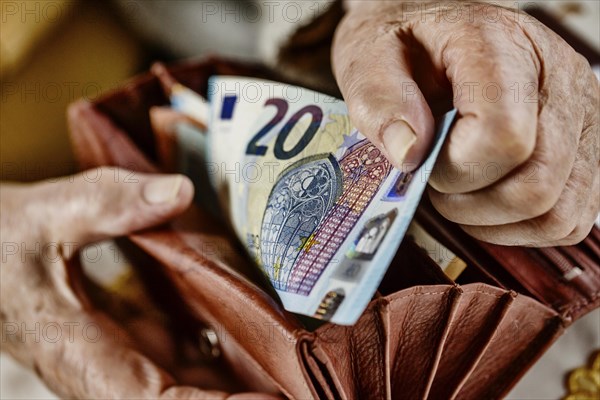 Senior citizen pulls a 20 euro note from her wallet