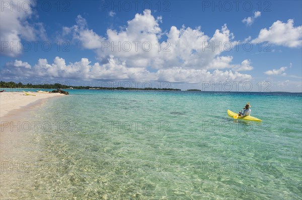 Female tourist kayaking in the turquoise waters of Tikehau