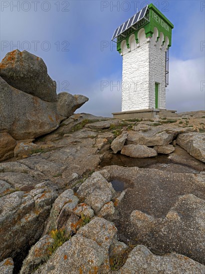 Green and white lighthouse on granite rocks