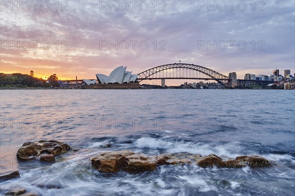 Sydney Opera with Harbour Bridge and skyscrapers at dusk