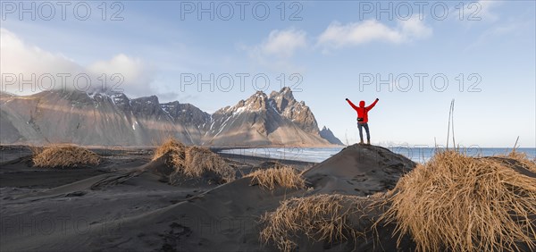 Man in red jacket stretches arms into the air