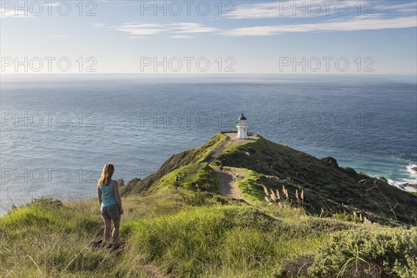Woman stands in front of lighthouse at Cape Reinga