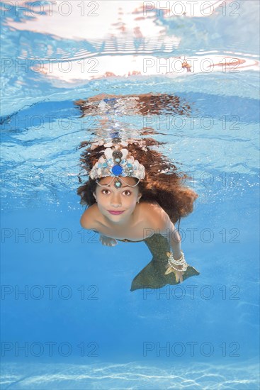 Girl in a mermaid costume poses underwater