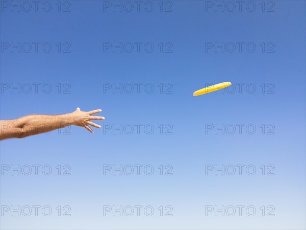 Man throwing a frisbee against blue sky