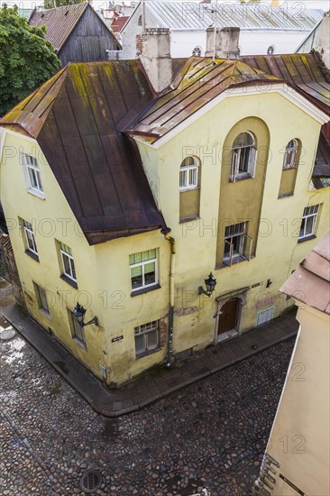 Top view of old architectural yellow with white trim and rusted standing seam sheet metal roof apartment building