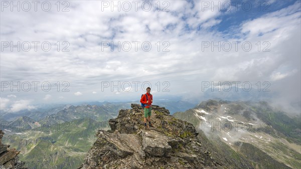 Hiker on the summit of the Hochgolling with rising fog