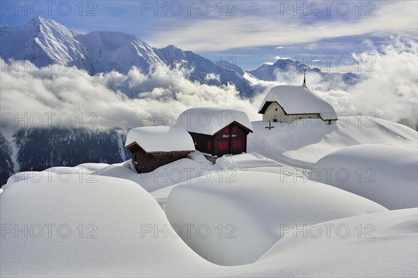 Maria zum Schnee chapel with snow-covered log cabins