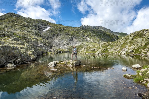 Hiker on a stone in a small lake