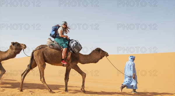 Tourist on a dromedaries with bedouin (Camelus dromedarius)