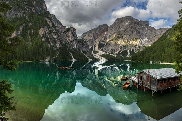 Green mountain lake with boats and boathouse