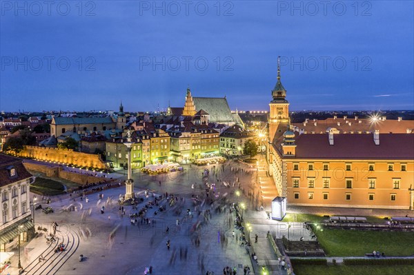 Royal Castle and Sigmund Column monument with many people passing by in the evening