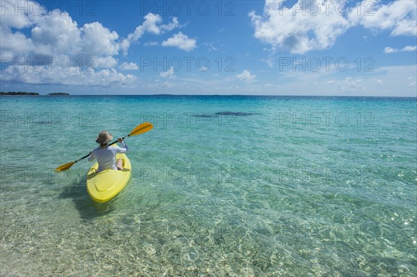 Female tourist kayaking in the turquoise waters of Tikehau