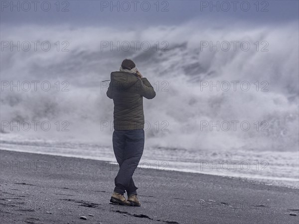 Tourist against storm waves at Reynisfjara Black Sand Beach