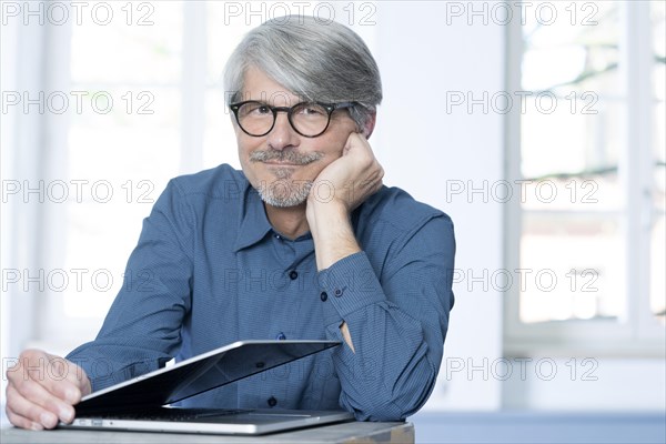 Man with laptop leaning on a desk