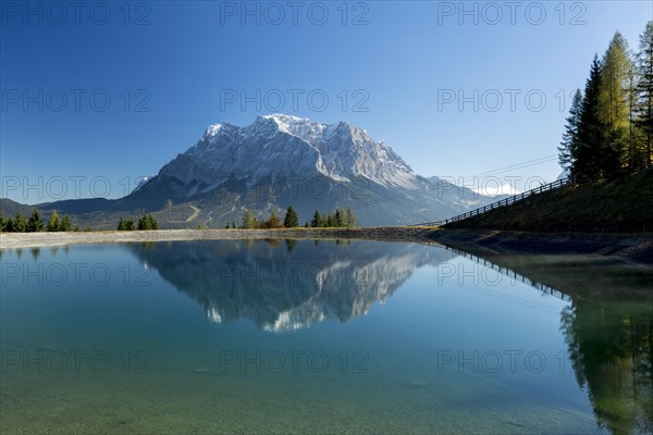 Water reservoir for snow production for the ski slopes on Grubigstein with view to the Zugspitze and mountain railway