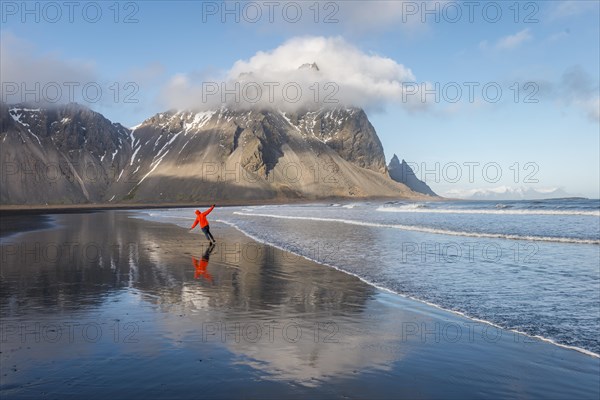 Man runs in a good mood on a black sandy beach