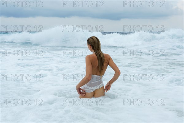 Young woman in a white shirt bathing in the ocean