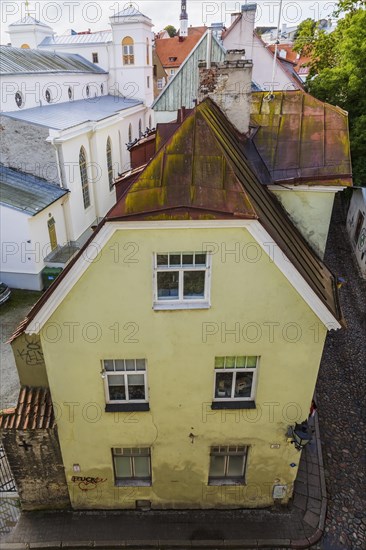 Top view of old architectural yellow with white trim and rusted standing seam sheet metal roof apartment building