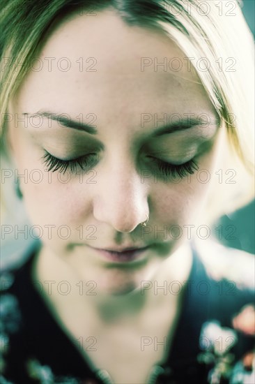 Young woman with closed eyes and nose piercing