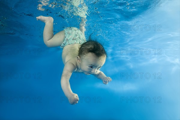 Little boy learns to dive underwater in the pool