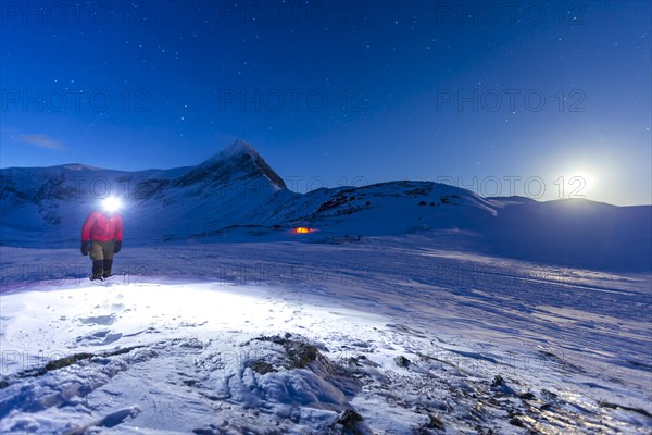 Person with tent on full moon in the snow