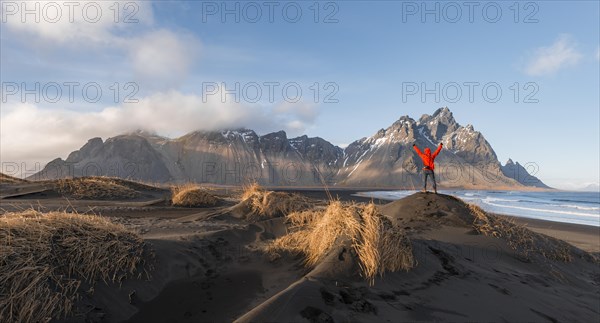 Man in red jacket stretches arms into the air