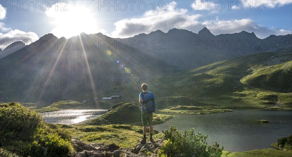 Hiker overlooks Unterer Giglachsee with morning sun