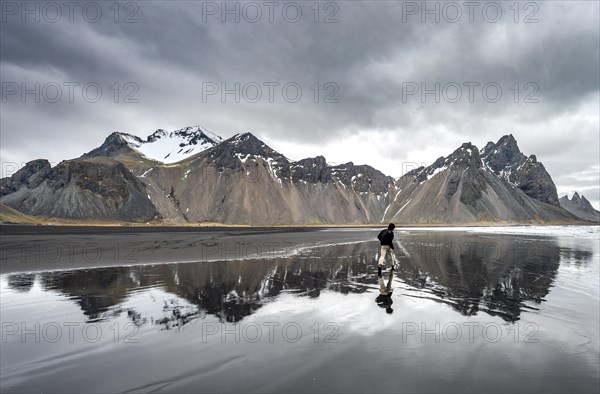 Hiker runs at the black sandy beach