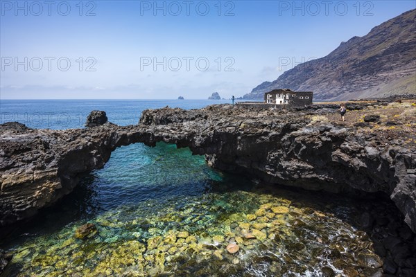 Black lava rock arch with Hotel Punta Grande