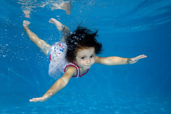 Little girl learns to swim underwater in the pool