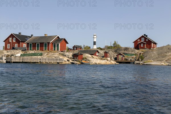 Red wooden houses with lighthouse on the rocky coast