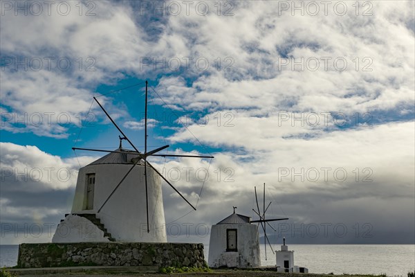 White windmills at the sea in front of cloudy skies