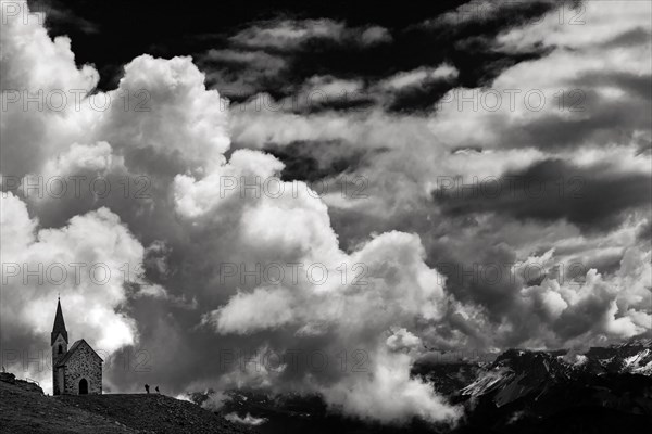 Latzfonser cross chapel with climber and dramatic clouds