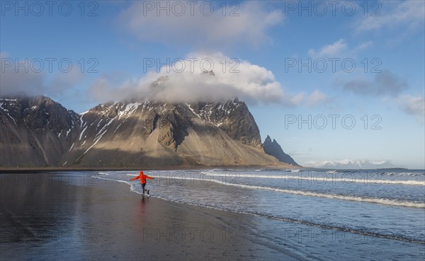 Man runs in a good mood on a black sandy beach