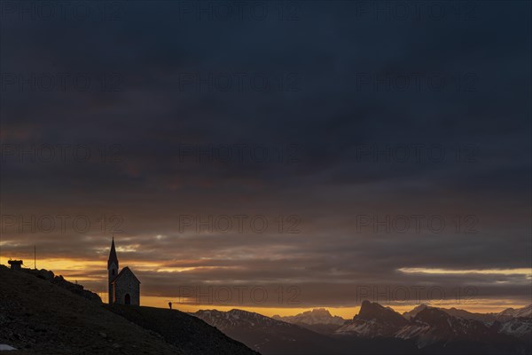 Latzfonser cross chapel at sunrise with dramatic clouds and South Tyrolean mountains