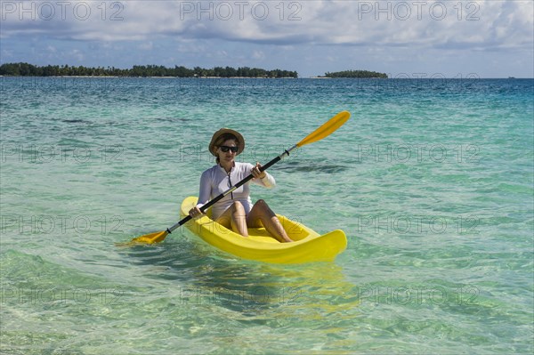 Female tourist kayaking in the turquoise waters of Tikehau